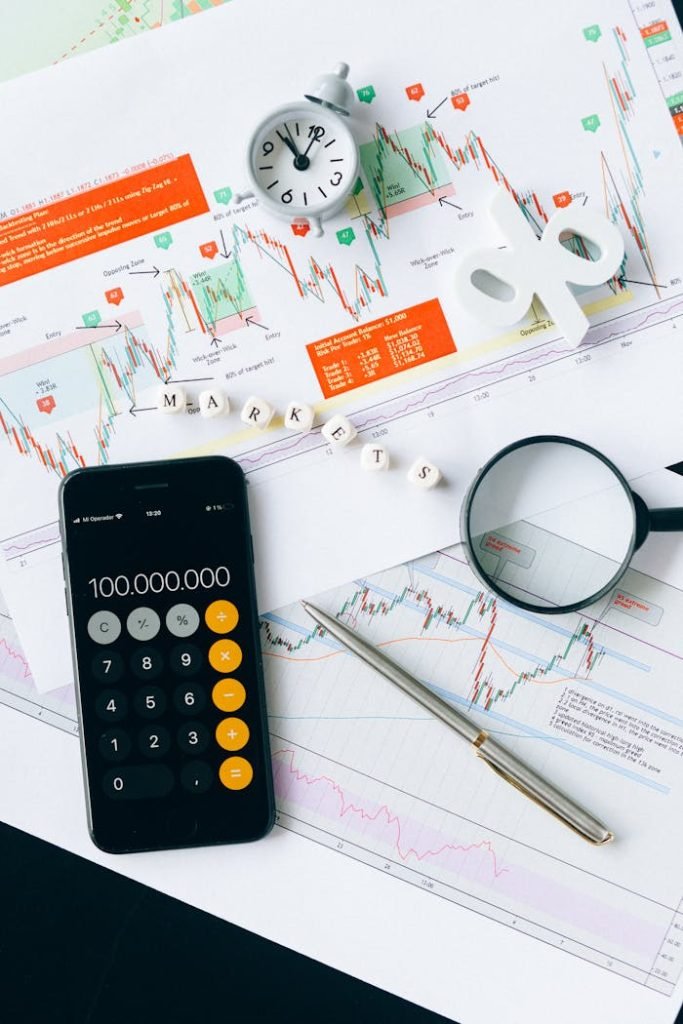 black-smartphone-on-white-paper-6120182 Flat lay of charts, calculator, and magnifying glass on office desk for market analysis.