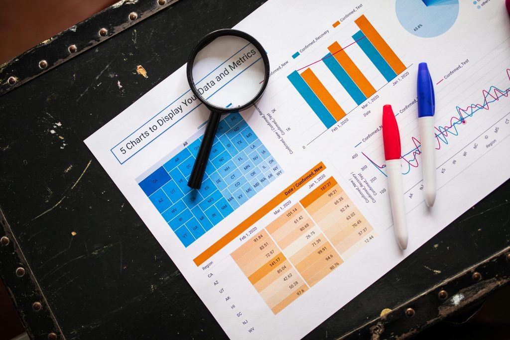 pexels-photo-7947750-7947750 Flat lay of business charts and graphs with magnifying glass and markers on a dark surface.