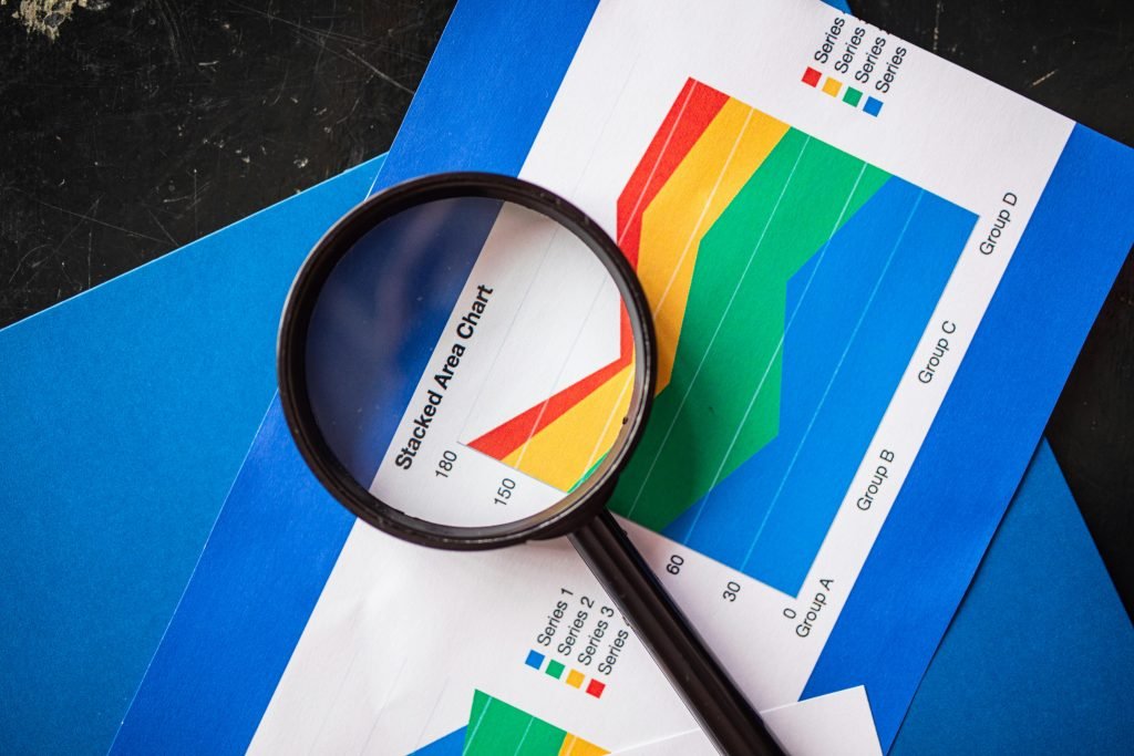 pexels-photo-7947753-7947753 Magnifying glass highlighting stacked area charts for business analysis.